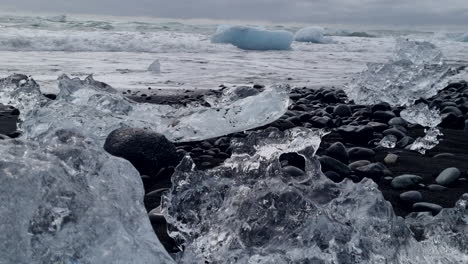 Schöne-Aufnahme-Von-Eisfragmenten,-Die-Am-Diamond-Beach-Gefunden-Wurden-Und-Den-Schwarzen-Sand-Und-Die-Wellen-Am-Ufer-Zeigen