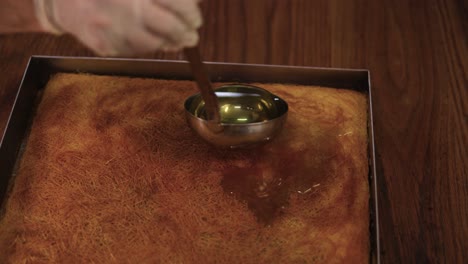 pastelero vertiendo el jarabe sobre la bandeja de postre con una cuchara de cocina