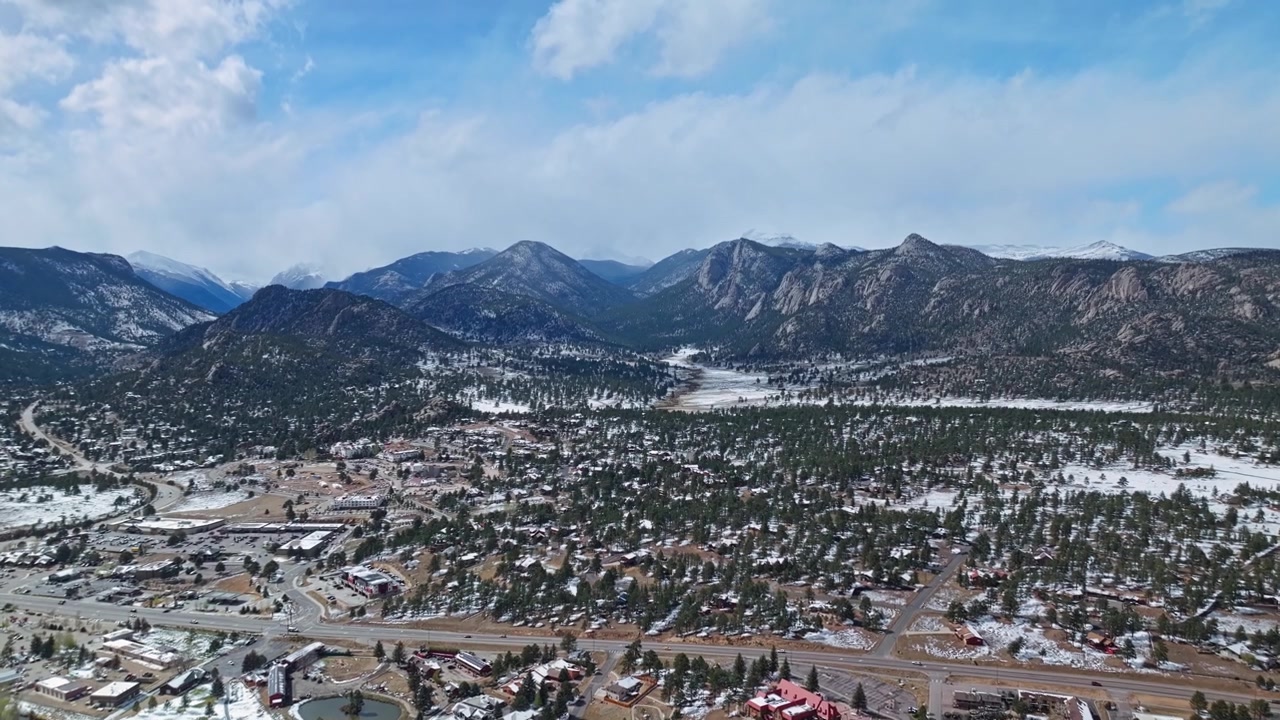 Area urbana di Estes Park con strade ed edifici circondata dal paesaggio delle Montagne Rocciose, panoramica aerea con drone.