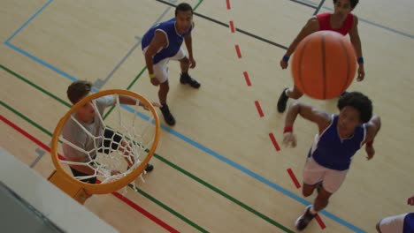 vista aérea de un jugador de baloncesto afroamericano marcando goles contra varios jugadores