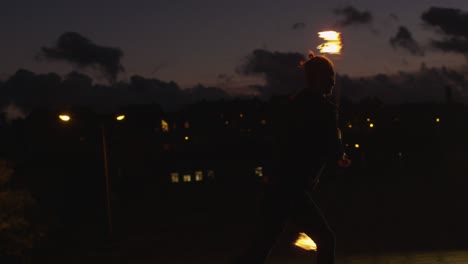 male artist performing fire show outdoors at evening time.