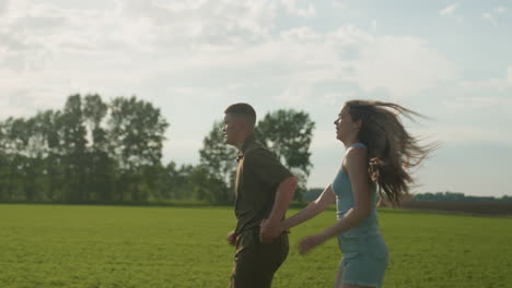 siblings running through open green field holding hands, woman long hair swaying in breeze, face showing tired breath and exhaustion, muscles flexing with each stride under clear sky