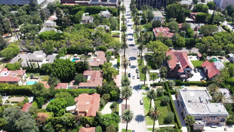 Un-Dron-Sigue-A-Un-Auto-Blanco-Conduciendo-Por-Una-Palmera,-Una-Calle-Bordeada-De-Casas,-En-El-Hermoso-Oeste-De-Hollywood,-California