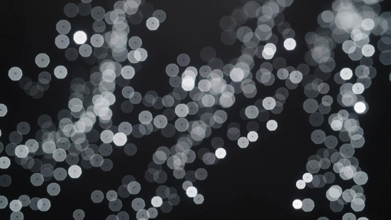 Campo de bokeh cambiante flotando en un estudio oscuro con fotogramas que avanzan revelando bordes poligonales.