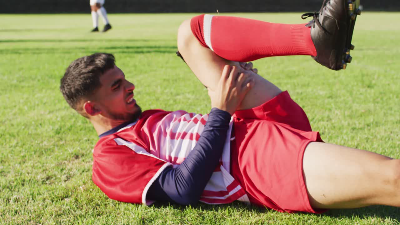 경기장에서 불법으로 누워있는 두 인종의 축구 선수의 비디오