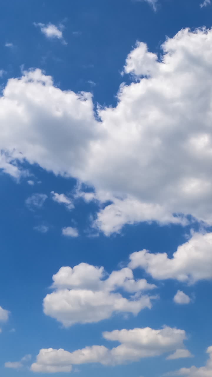 Soft beautiful clouds forming in the blue sky. Clouds flying quickly in the rays of sun. Timelapse. Vertical video