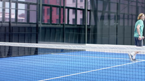 People playing padel tennis on blue indoor court, focusing on hitting ball