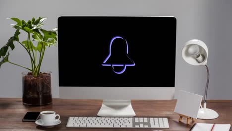 animation of an icon of a bell flickering on screen of a desktop computer standing on a wooden desk