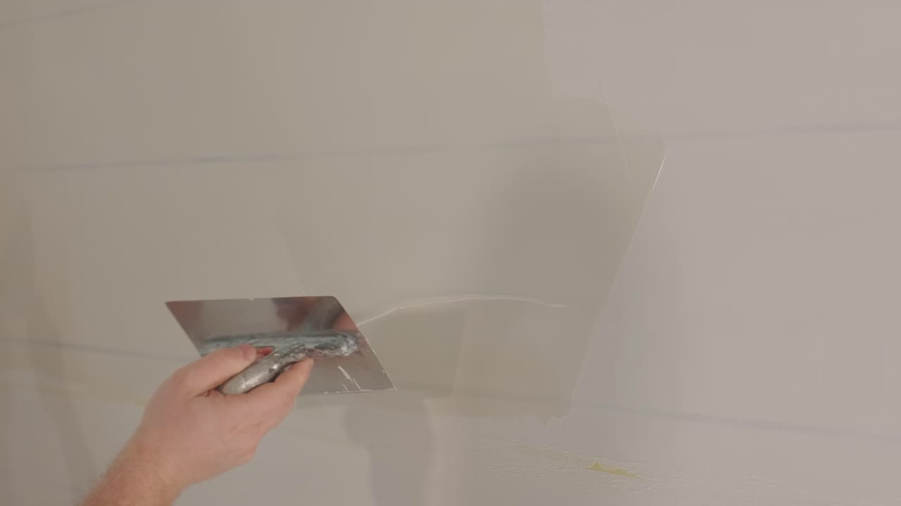 Man plastering the walls with finishing putty in room with putty spatula