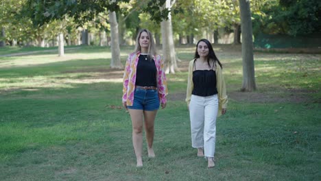two women walking barefoot in a park