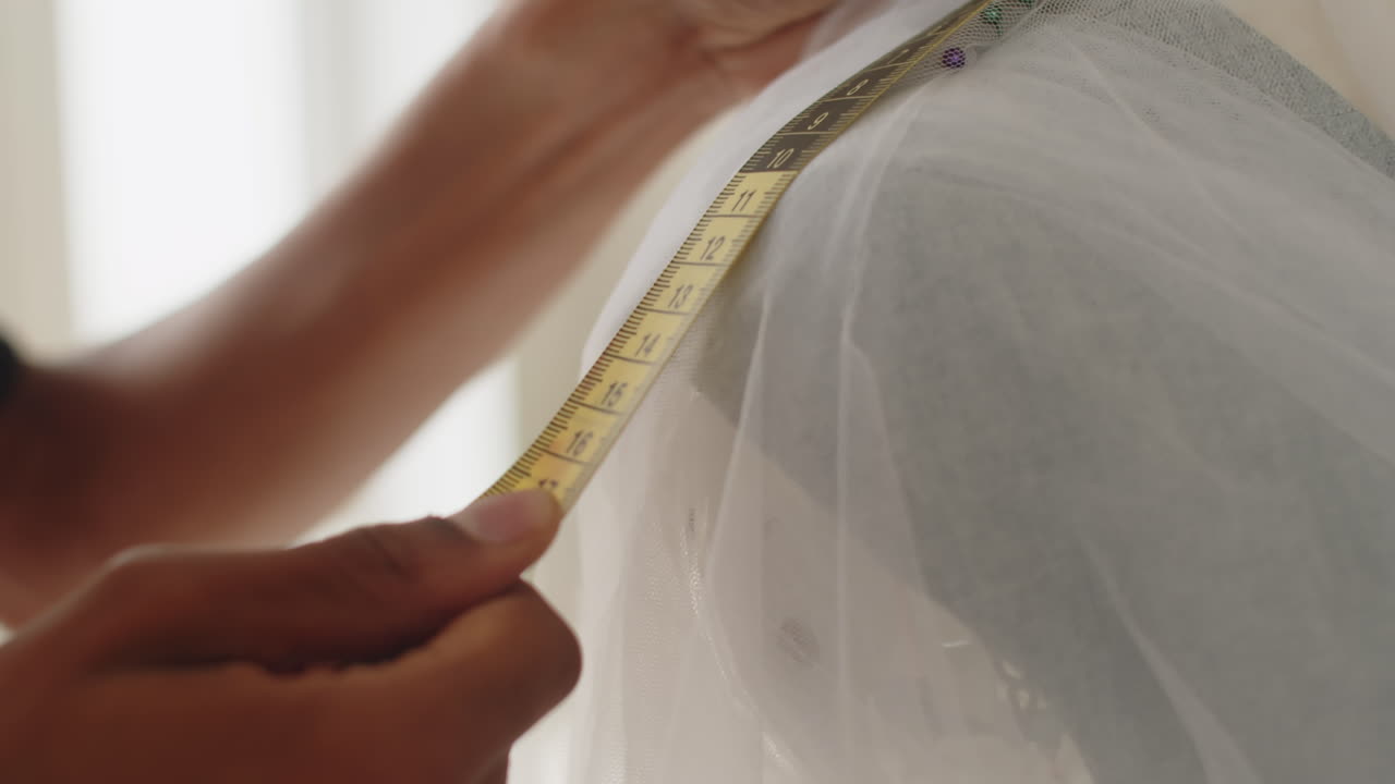Modista midiendo el largo de las partes de un vestido de novia
