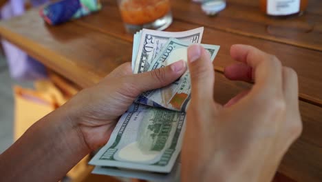 woman counting the united states $100 dollar bills and $50 dollar bill, paper currency