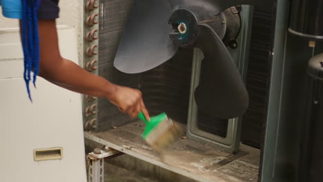 mechanic sweeping debris in hvac unit