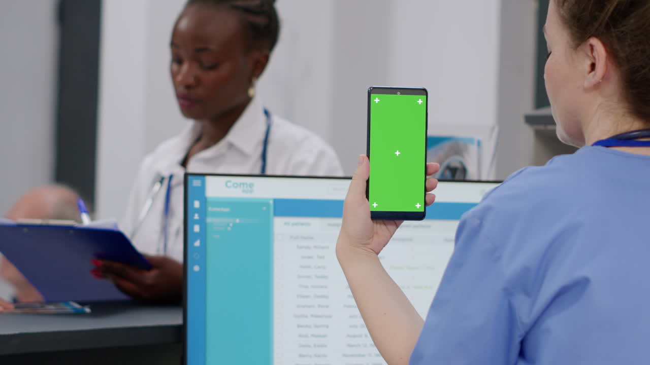 Healthcare professionals using a mobile phone with a green screen in a clinic