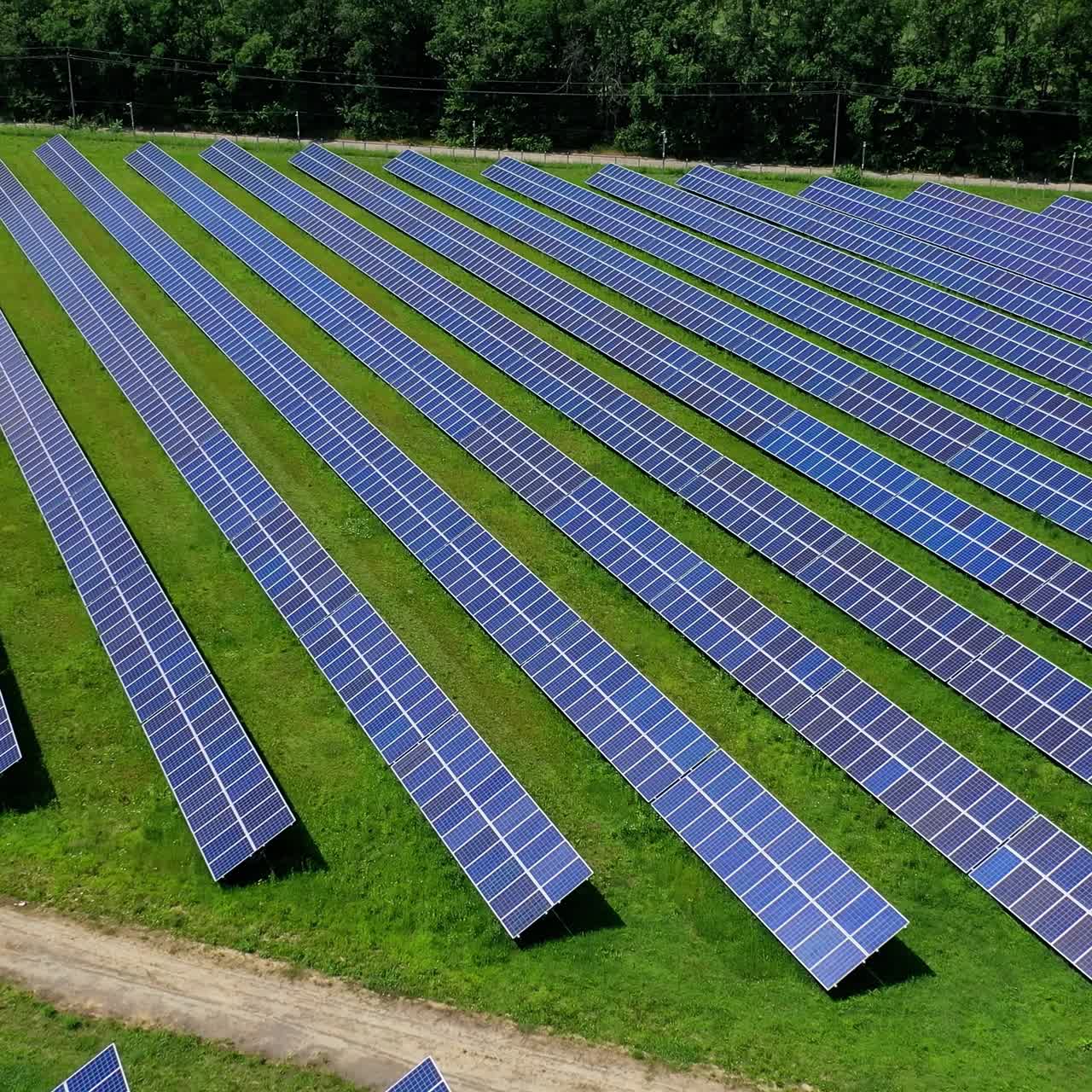 Power energy solar farm in the countryside. Photovoltaic solar batteries near the forest in bright summer day. Alternative source of clean energy. Aerial view