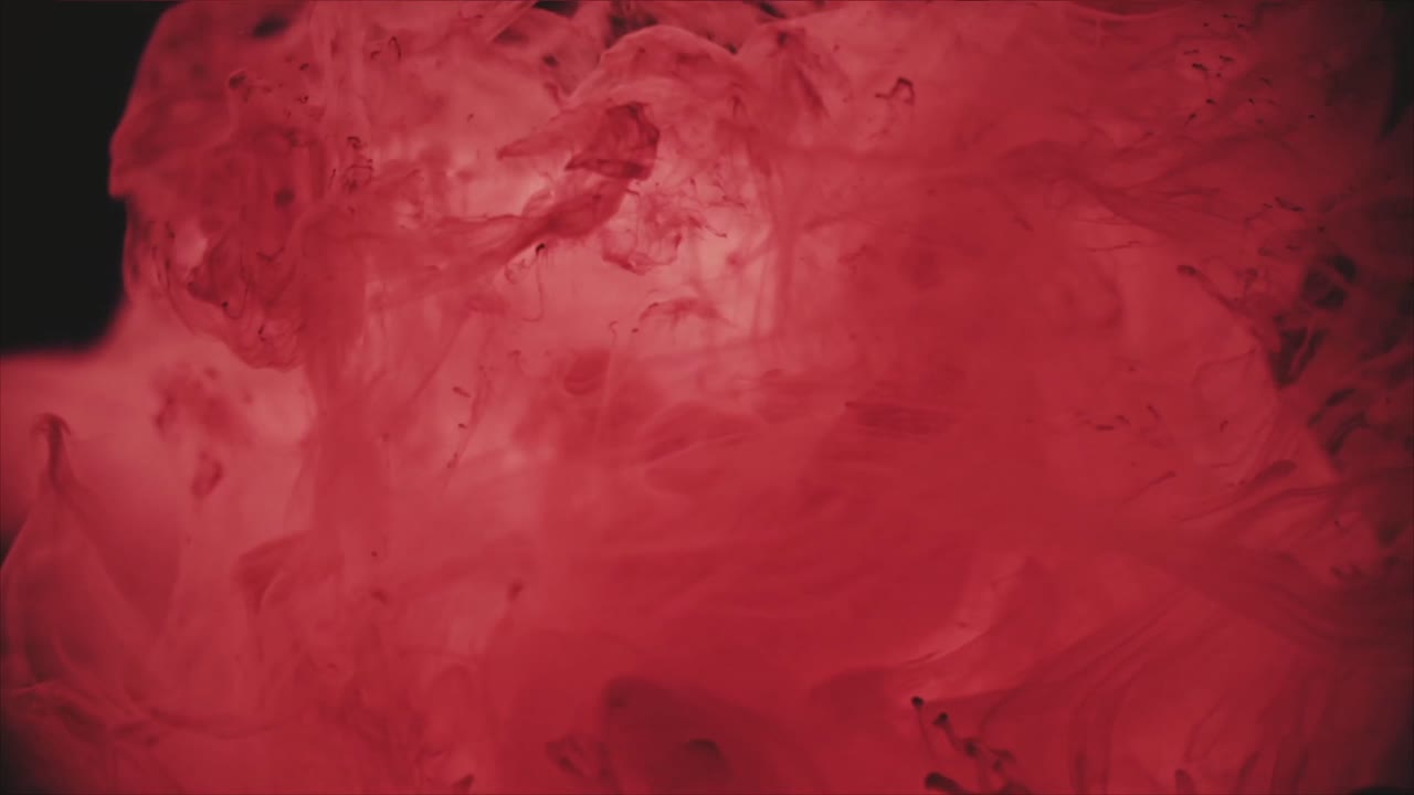 Inchiostro rosso vibrante che si dissolve in acqua su sfondo nero