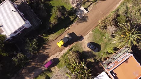 Vista-Circular-Aérea-De-Arriba-Hacia-Abajo,-En-Una-Máquina-De-Nivelación-Amarilla-Que-Trabaja-En-La-Construcción-De-Una-Nueva-Carretera-En-Una-Zona-Residencial-De-Uruguay