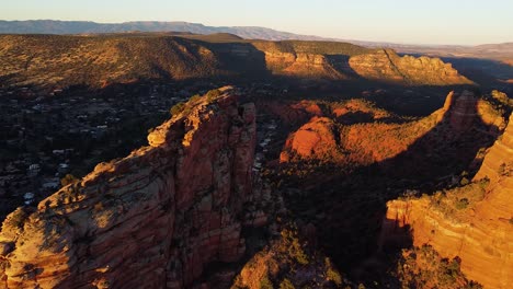 orange sandstone mountain valley in early morning during bright golden sunrise, aerial drone shot