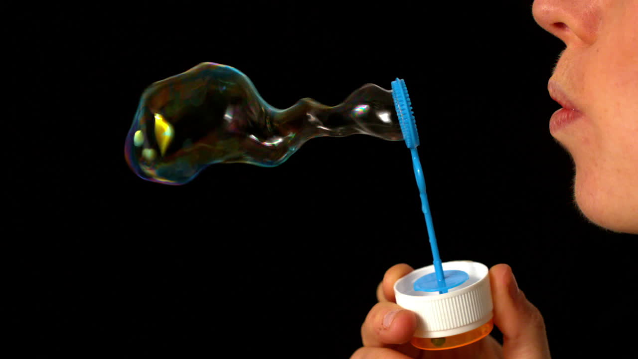 donna che soffia bolle su sfondo nero