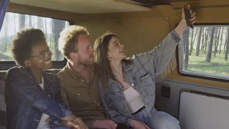 three friends take a selfie of them inside a caravan during a roadtrip