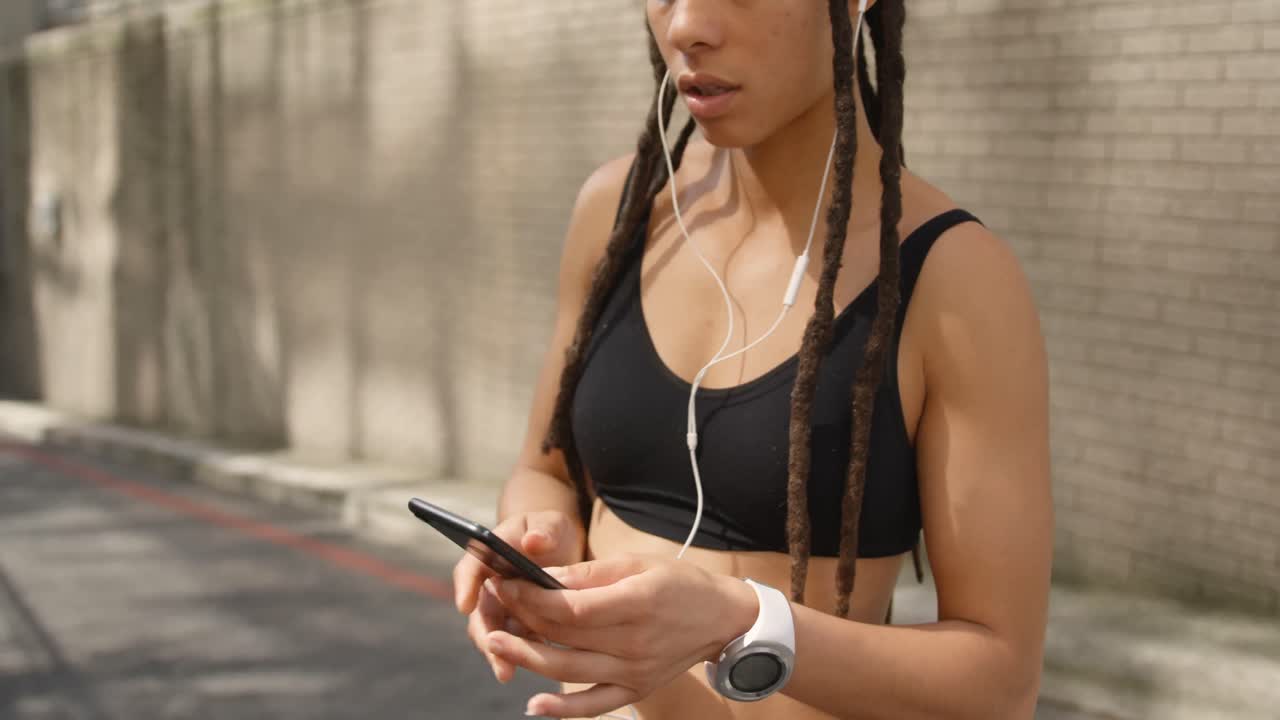vista frontal de una mujer afroamericana usando un teléfono móvil en la ciudad 4k