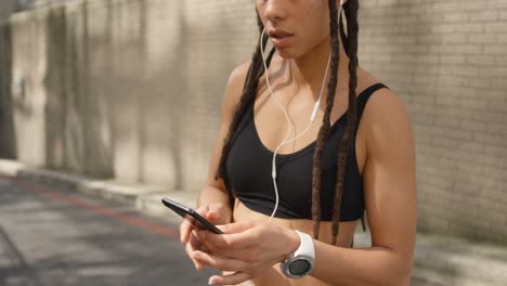 vista frontal de una mujer afroamericana usando un teléfono móvil en la ciudad 4k