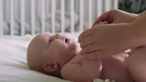 close up of unrecognizable woman playing with her newborn baby lying on the bed