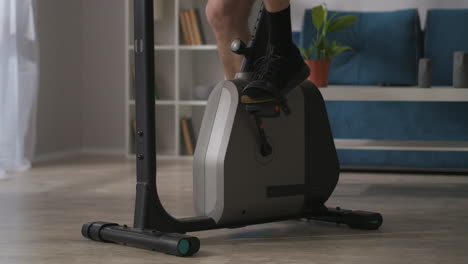 person is training alone in home using stationary bike for keeping fit closeup of legs on pedals fitness and wellness concept