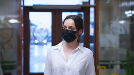 cute young woman hotel guest wearing protective mask to protect from coronavirus. girl enters a hotel in white shirt.