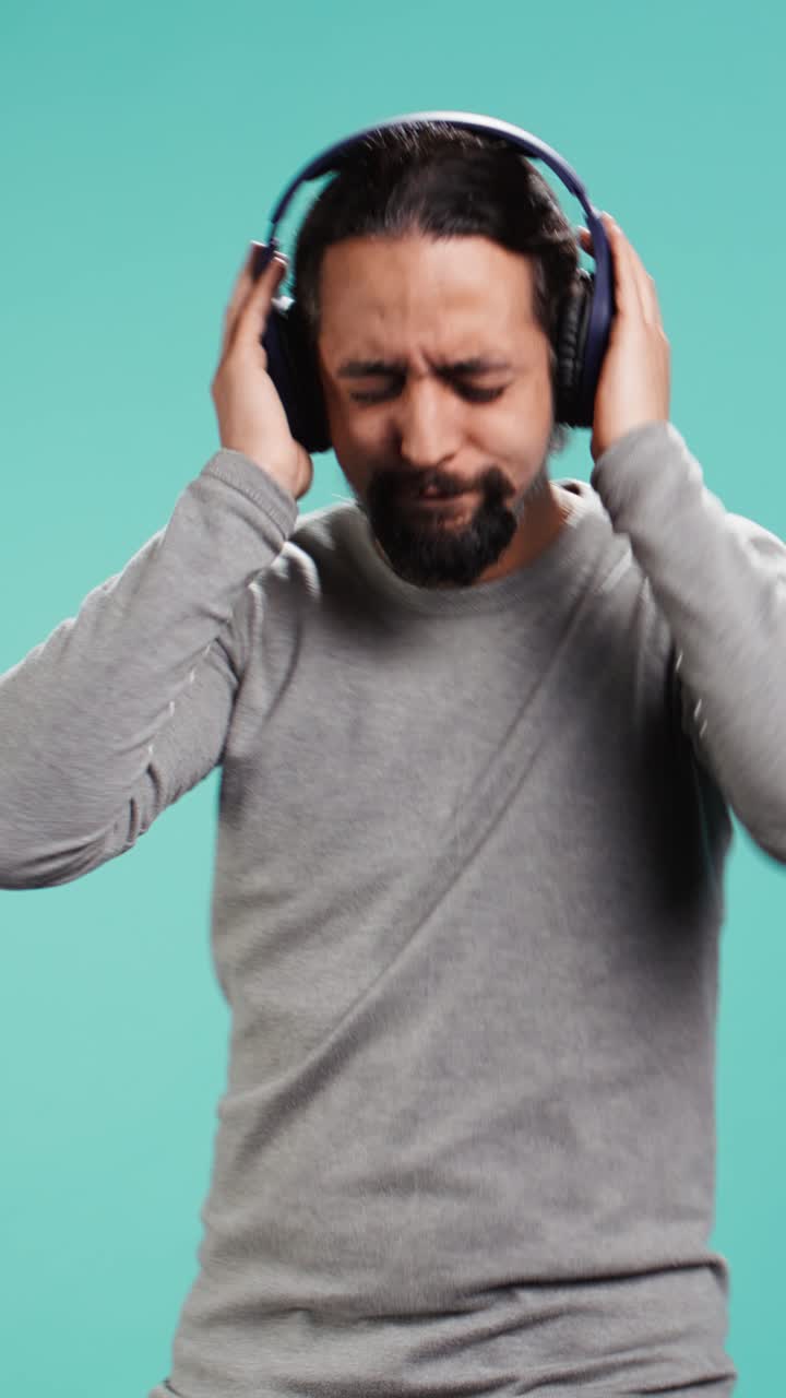 Video verticale. Uomo che ascolta musica ad alto volume con cuffie stereo wireless