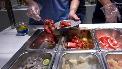 el cocinero está tomando carne cruda del tanque de metal para cocinar en todo lo que pueda comer restaurante
