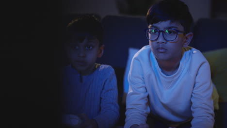 Front-View-Of-Two-Young-Boys-At-Home-Having-Fun-Playing-With-Computer-Games-Console-On-TV-Holding-Controllers-Late-At-Night-5