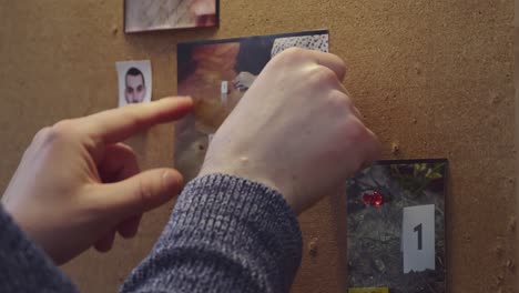 Detective&#039;s hands put the crime scene photo on the evidence board