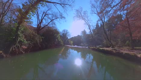 autumnal fpv drone flight above a river, waterfall, and forest with glorious sunlight