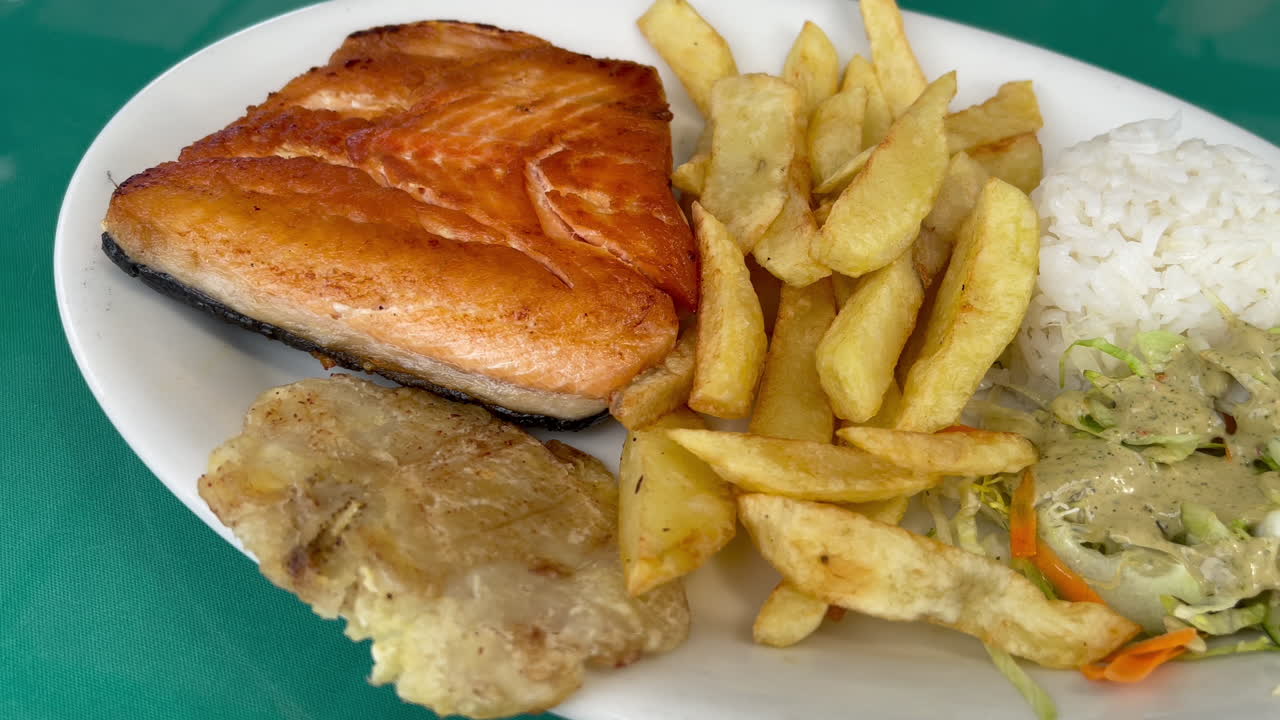 Piatto gourmet con pesce, riso, patate croccanti e insalata.