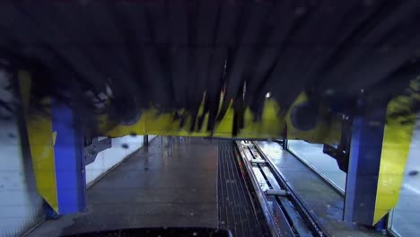 lavado automático de autos visto desde la parte trasera del vehículo moviéndose a través de los rodillos de la máquina