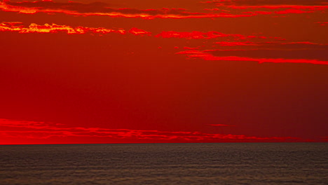 half circle sun rising in the horizon on a red fiery sky background, time lapse