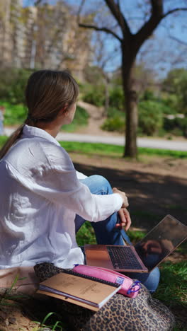 woman studying outdoors in a park with laptop