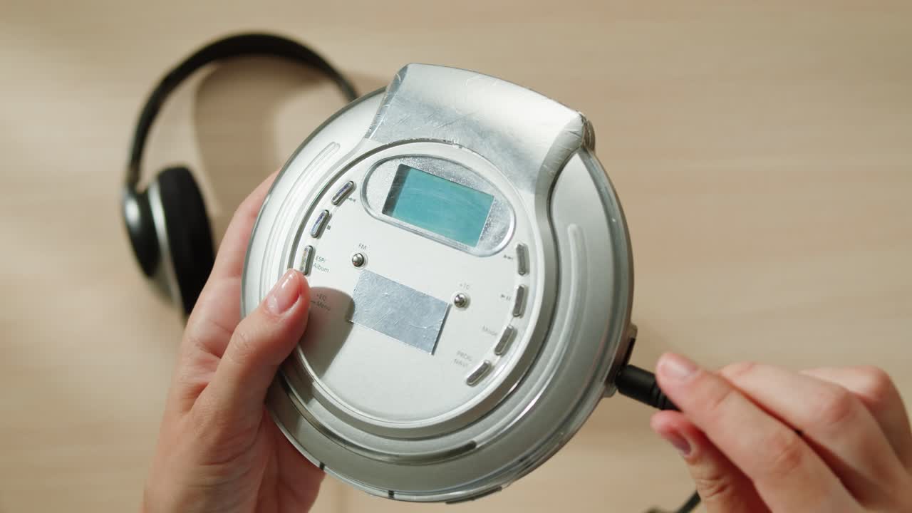 헤드폰과 함께 빈티지 휴대용 cd 플레이어를 들고 있는 사람