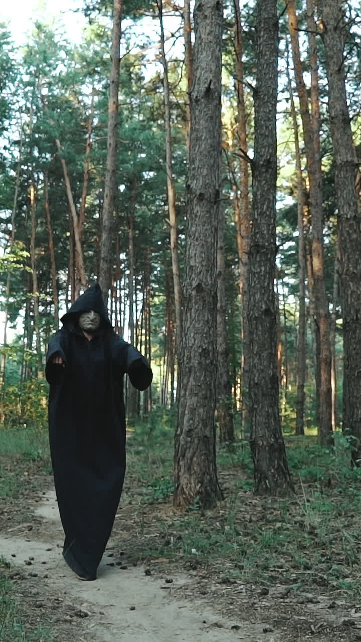 Evil ghost hooded creature walking across forest. Halloween. Vertical video