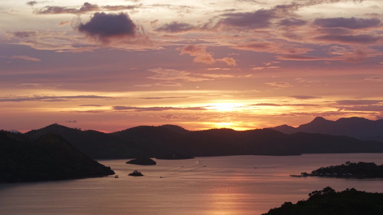 Toma estática de dron con teleobjetivo que captura nubes a la deriva sobre la Bahía de Coron, atardecer en Palawan.
