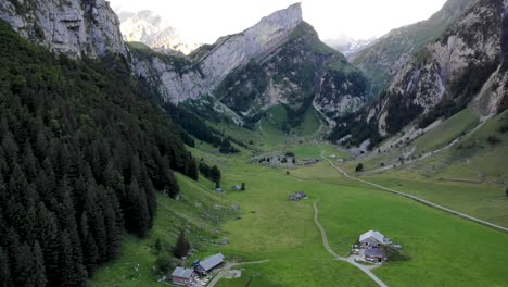 Aerial-flyover-from-the-shore-of-lake-Seealpsee-in-Appenzell,-Switzerland-towards-the-water-with-a-reflection-of-the-Alpstein-peaks-on-the-lake's-surface-being-revealed