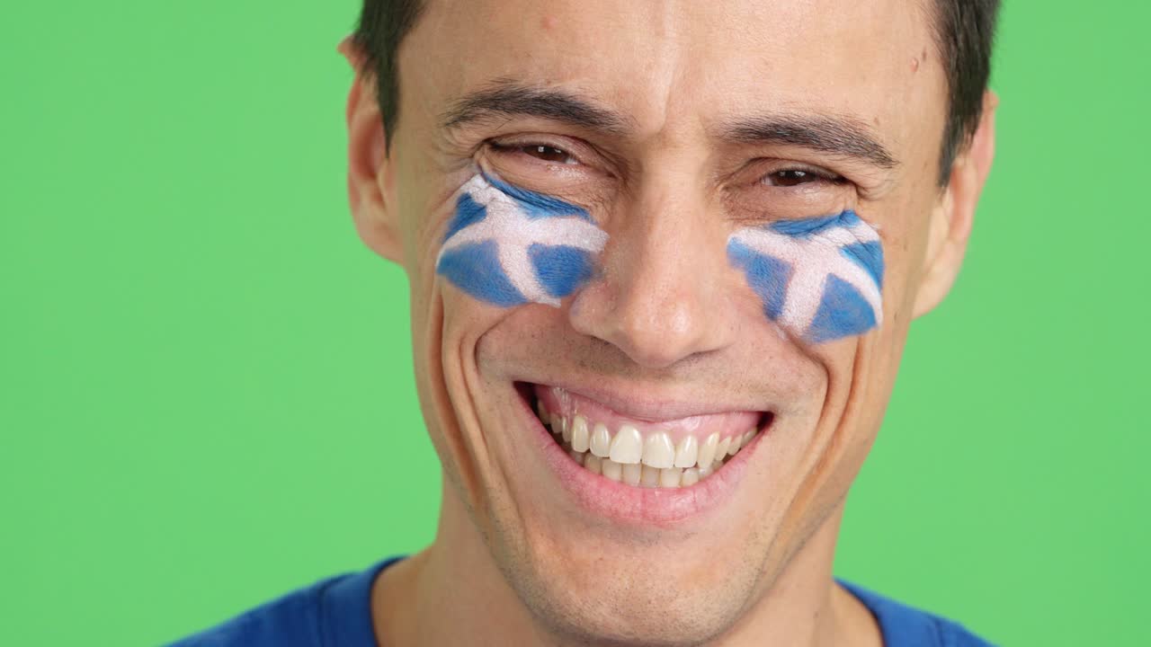 Man with a scottish flag painted on the face smiling