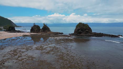 a mesmerizing drone shot captures a small island and a rocky mountain at the edge of the shore, with the vast ocean stretching out in the background.