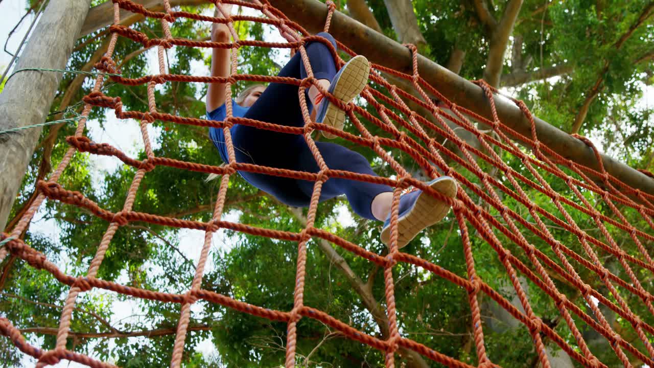 Fit woman climbing a net during obstacle course 4k