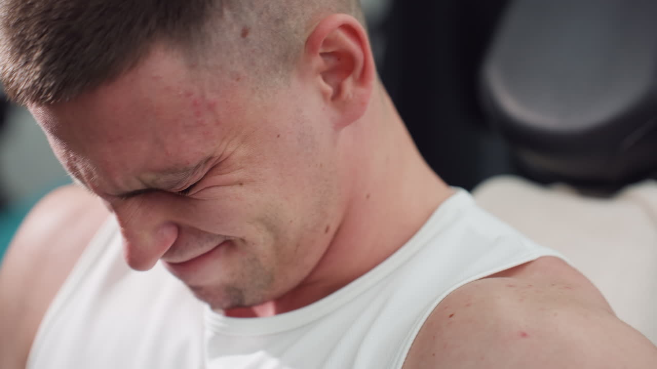 Body builder facial strain working out on leg extension machine demonstrating focused power and controlled motion under intense gym lighting. Tense calves and quads drive strength and endurance