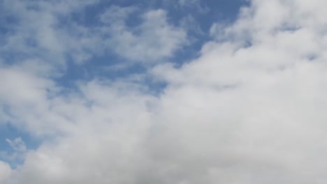 Animation-of-white-clouds-moving-fast-in-seamless-loop-over-blue-sky