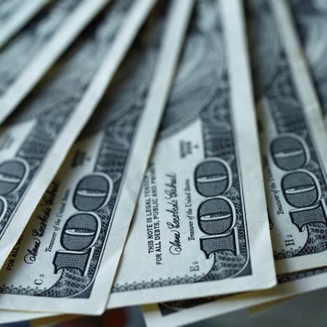 rich background of one hundred dollars. american money rotating slowly. a lot of paper banknotes of dollar bills spinning. close-up.