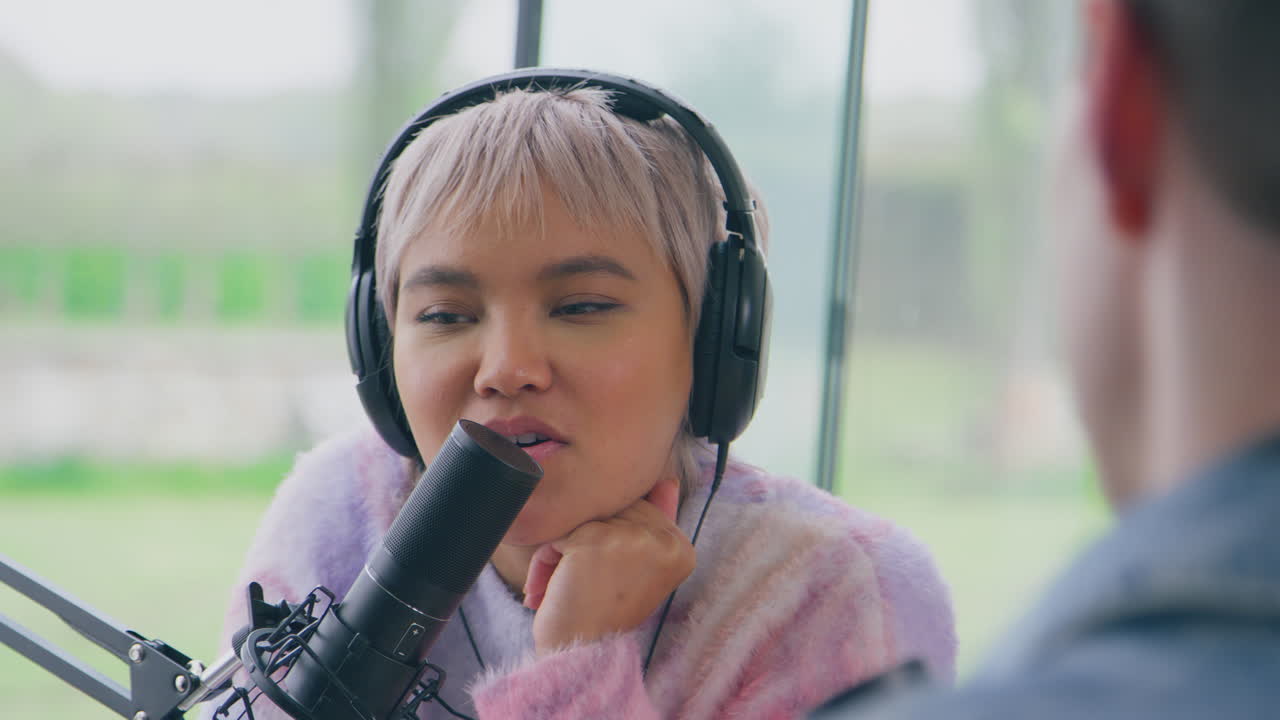 헤드폰을 착용한 커플이 마이크로폰으로 라이브 스트리밍을 하며 웃고 이야기하고 있습니다.