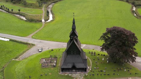 aerial view, hopperstad black wooden stave catholic church and cemetery, norway, ancient religious norwegian monument in green summer landscape, drone shot